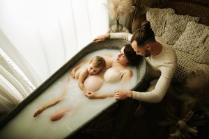 Séance photo grossesse en famille, avec le papa et les enfants dans un décor chaleureux